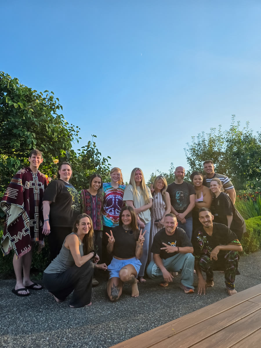 Participants gathered outdoors at dusk against soft greenery