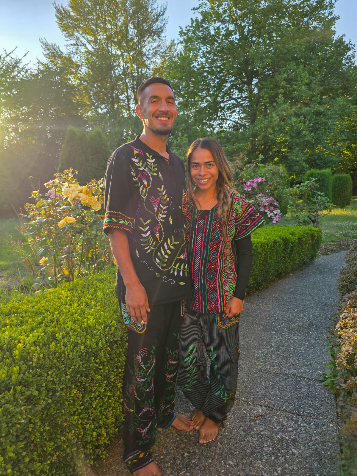Two facilitators in embroidered Shipibo garments in the garden at golden hour