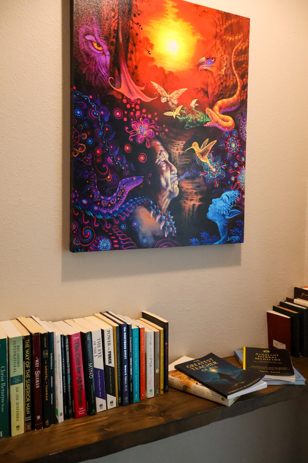A vibrant visionary painting above a shelf of spiritual and integration books in the reflection space